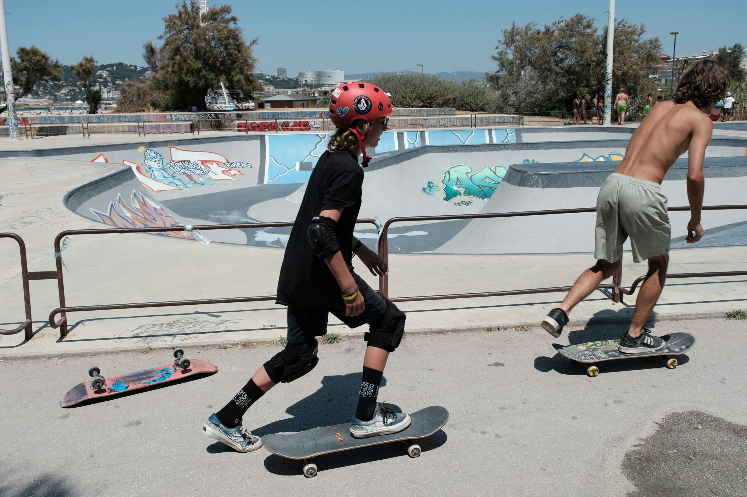 Person skater med et komplet beskyttelsessæt. Personen har hjelm, albuebeskyttere, håndledsbeskyttere og ankelbeskyttere på. I baggrunden ses skaterparken med dens ramper og graffiti. Person skater med et komplet beskyttelsessæt. Personen har hjelm, albuebeskyttere, håndledsbeskyttere og ankelbeskyttere på. I baggrunden ses skaterparken med dens ramper og graffiti.