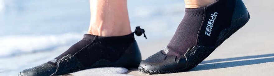 Person går på sand med neoprensko på