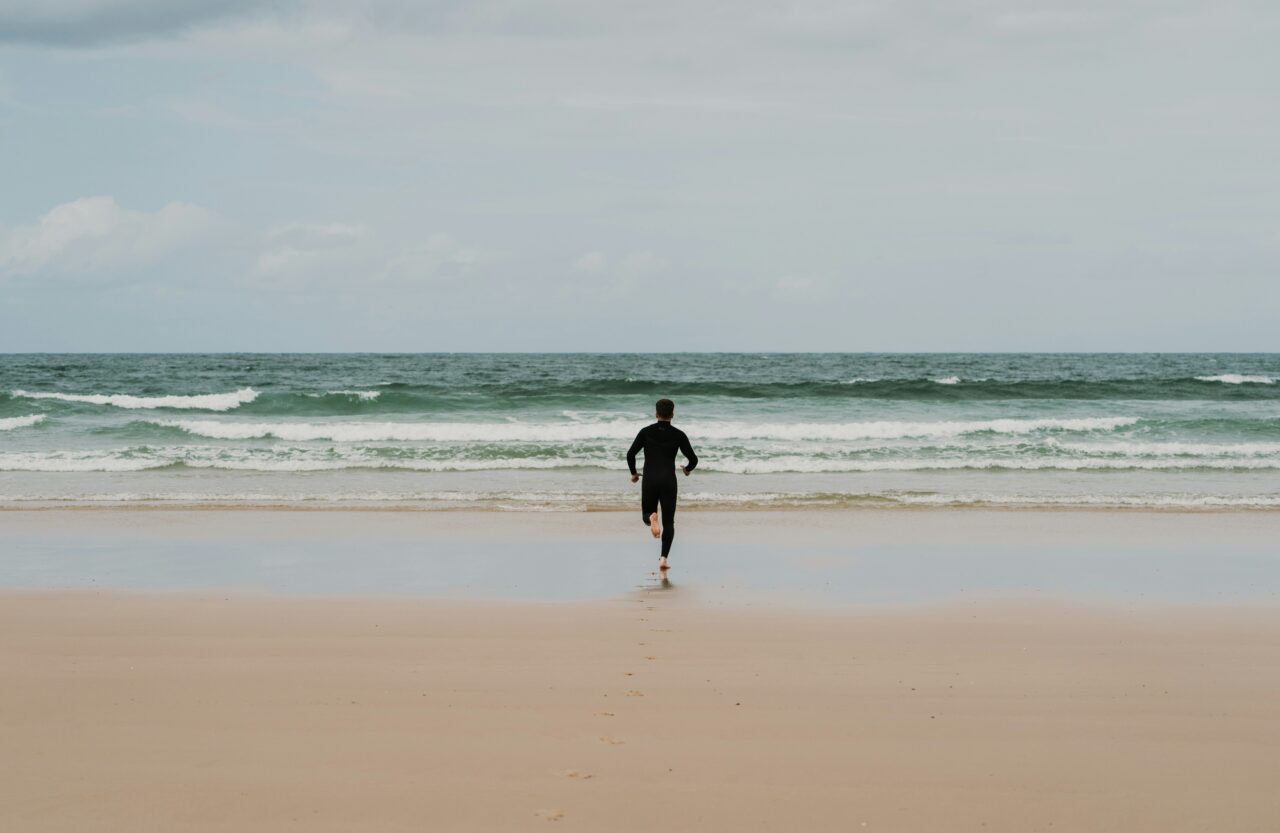 motoki tonn s4TkEVKM8Gw unsplash scaled Person løber ud mod bølgerne i en våddragt