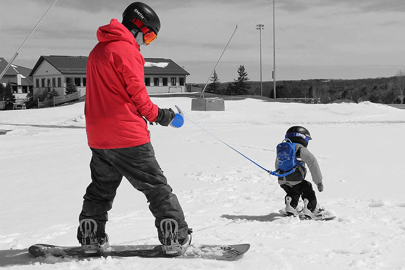 En voksen bruger en skisele for at hjælpe med at lære et barn at stå på ski